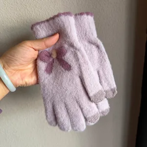 Détail de gants tricotés violet clair avec nœud décoratif et bout des doigts tactile