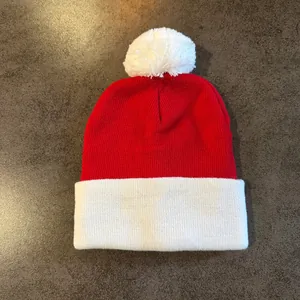 Close-up of red and white knitted beanie with a white pompom and fold-over cuff