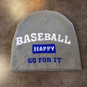 Detail of grey knitted beanie featuring BASEBALL HAPPY GO FOR IT jacquard text design