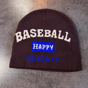 Detailed knit texture of a dark purple beanie featuring baseball and happy jacquard text