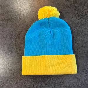 Detail shot of the knit beanie showing blue and yellow color blocking and pom-pom texture