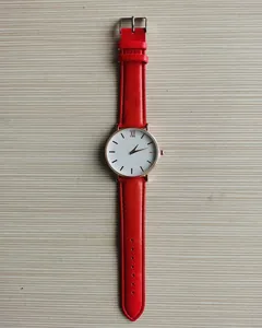 Dettaglio dell'orologio al quarzo con cinturino in pelle rossa e quadrante oro rosa minimal
