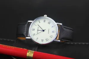 Macro shot of Geneva quartz watch with white Roman dial and black leather strap on desk