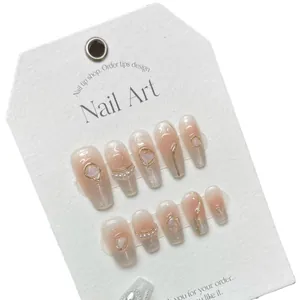 Handmade gradient pink press-on nails with pearls, gold lines, and 3D heart gems