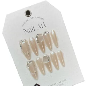 Faux ongles amande rose nude avec chaînes argentées et cristaux de strass brillants