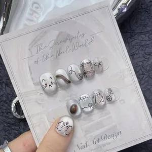 Détails de faux ongles argentés nacrés avec motifs de chats et nœuds faits à la main