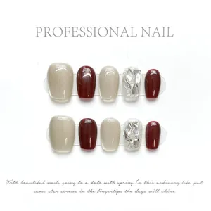 Close-up of wine red and cat-eye beige press-on nails with silver glitter accents