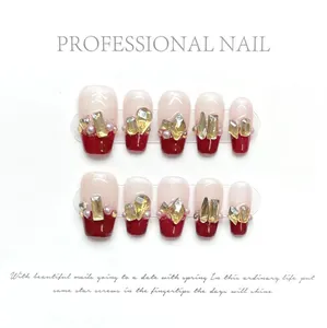 Detail of handmade press-on nails with red French tips, gold rhinestones and pearls
