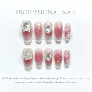 Detailed view of handmade red and silver gradient press-on nails with rhinestones and charms