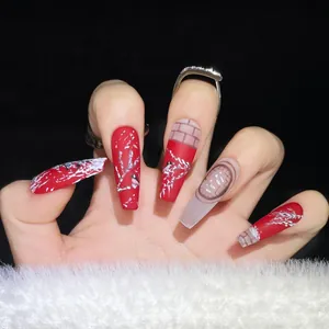 Detail of red press-on nails with white snowflake art and dark plaid patterns