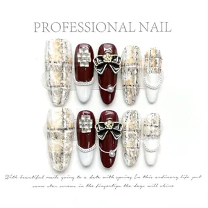 Detail of handmade press-on nails featuring red tweed, gold camellia, and pearl accents