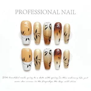 Detail of handmade press-on nails featuring golden glitter and black bamboo leaf patterns