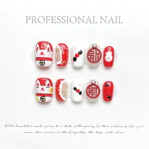 Detail of handmade press-on nails featuring red and white lucky cat and 3D relief patterns