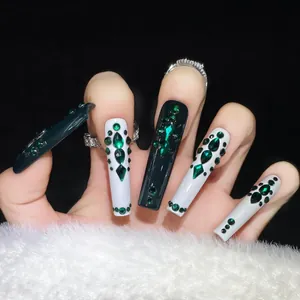 Macro shot of long emerald coffin press-on nails with sparkling rhinestones and gems
