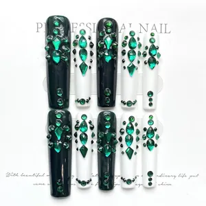 Detail of luxury emerald green press-on nails with intricate rhinestone embellishments