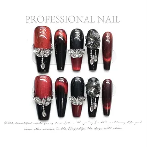 Detailed view of red and black cat-eye press-on nails with luxury rhinestones and charms