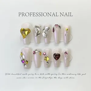 Dettaglio di unghie finte artigianali con glitter argento, strass e ciondoli a cuore