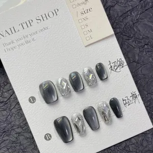 Dettaglio di unghie finte artigianali effetto cat-eye con strass su scheda display