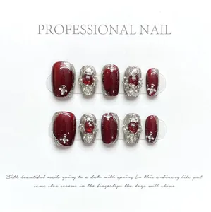 Detail of handmade burgundy cat-eye press-on nails with pearls and rhinestones