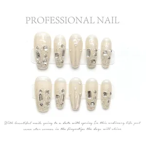 Detail of handmade nude pink press-on nails with silver glitter gradient and rhinestones
