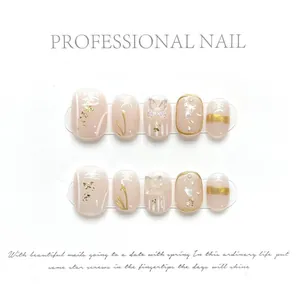 Detail view of pink press-on nails with gold foil, 3D butterfly, and pearl accents