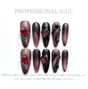Macro detail of handmade gothic press-on nails with dark cat-eye effect and red rhinestones