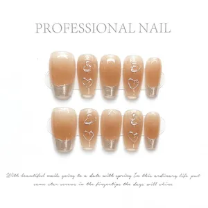 Macro view of nude tone press-on nails with silver French tips and heart line patterns
