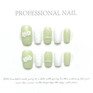 Close-up of mint green press-on nails with 3D white flowers and pearl accents