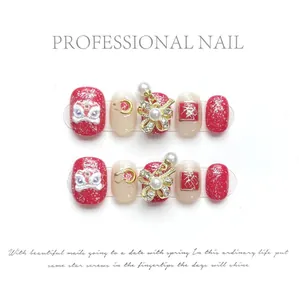 Detail of red and beige press-on nails with 3D lion dance motifs and gold bows