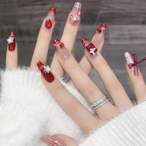 Gedetailleerd beeld van handgemaakte Franse kunstnagels in rood met strikjes en stenen