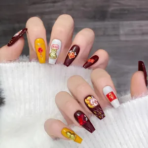 Detail of red and yellow handmade press-on nails with 3D lucky charms and character art