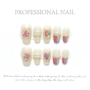 Detail van handgemaakte kunstnagels met parels, gouden lijnen en wit-paars kleurverloop decor