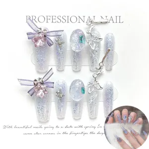 Detalle de uñas postizas lavanda con dijes de mariposa y purpurina en forma de ataúd