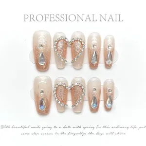 Macro detail of handmade press-on nails with rose gold glitter and heart diamond accents