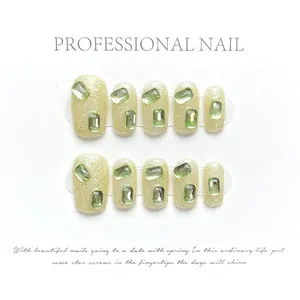 Macro-opname van groene press-on nagels met glitterbasis en fonkelende groene edelstenen