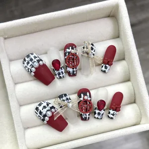 Handmade red matte press-on nails with tweed patterns and festive gold charms