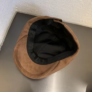 Detailed interior of a brown suede newsboy cap featuring black lining and sweatband