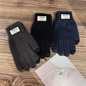 Detailed view of three pairs of winter touch screen knitted gloves on a wooden desk