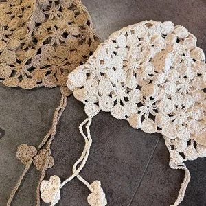 Détails de deux bonnets au crochet faits main avec fleurs et liens à pompons beige et blanc