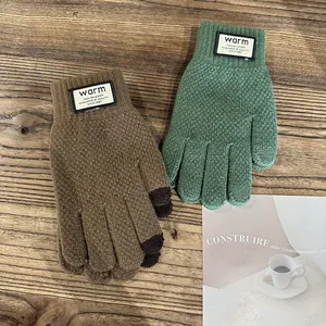 Detail view of thick knit winter gloves with touchscreen fingertips on a wooden background