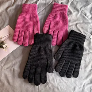 Détail de gants tactiles en tricot rose et noir avec poignets élastiques côtelés