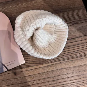 Vue détaillée de dessus d'un bonnet en tricot côtelé crème sur une table en bois rustique