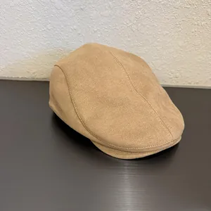 Detail view of the camel suede flat cap showing stitched panels and curved brim