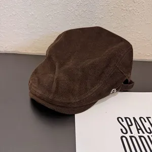 Détail macro d'un béret en velours côtelé marron foncé avec texture fine et broderie latérale