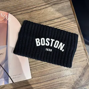Détail du bandeau en maille noire avec texte blanc BOSTON. 1630 sur fond en bois