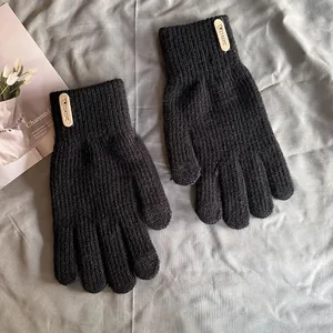 Détail d'un gant en tricot noir avec texture côtelée et étiquette en cuir classique