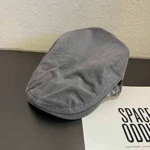 Détail d'une casquette plate en velours côtelé gris avec broderie et texture douce