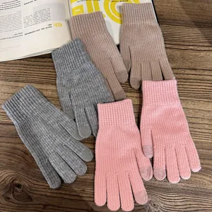 Detailed close-up of knitted touchscreen gloves in grey pink and brown on wooden surface