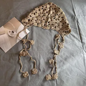 Détail du foulard au crochet beige avec broderie florale et de longs pompons