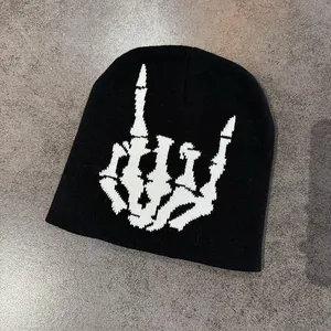 Flachliegende schwarze Strickmütze mit weißem Skeletthand-Stickerei auf Steingrund